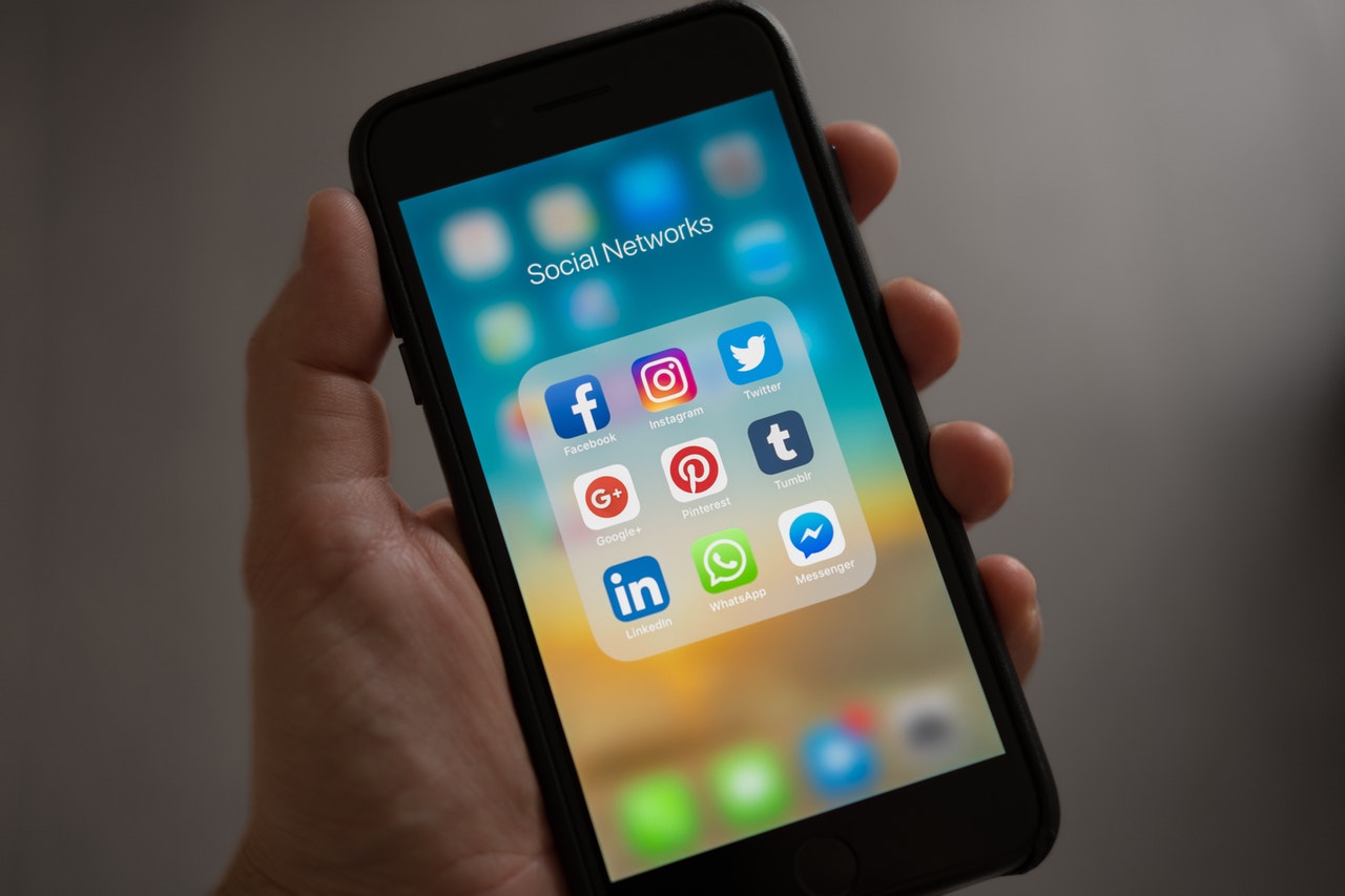 Dłoń trzymająca telefon, który na ekranie wyświetla ikony social media